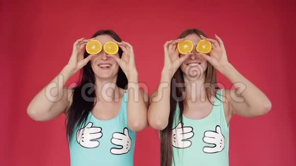 快乐的姐妹们涉猎玩橘子鲜艳的宣传视频带橘子的红色背景上的布吕尼视频的预览图