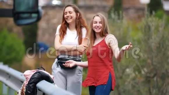 两个年轻的笑女在街上说话视频的预览图