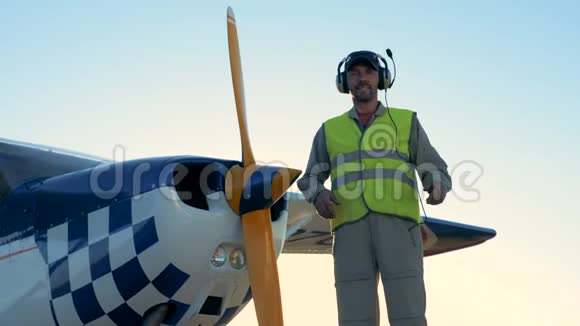 飞行员靠近小飞机戴着耳机站在跑道上视频的预览图