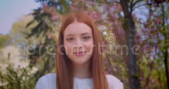 迷人的姜女学生穿着白色衬衫在粉红色的花园里梦幻般地看着视频的预览图