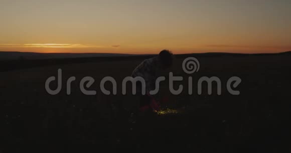 玩可爱的男孩与飞机和手电筒在日落通过田野4k视频的预览图
