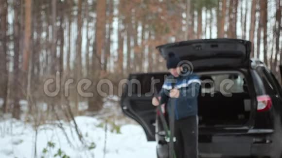在冬天的森林里人们和滑雪板站在汽车附近视频的预览图