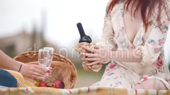 两个女人坐在毯子上野餐在酒杯里倒红酒托斯卡纳视频的预览图