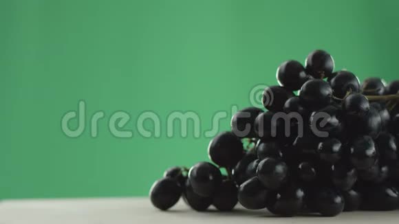 在视频中我们看到一串葡萄两颗葡萄从一串串的绿色背景上滚动在桌子上视频的预览图