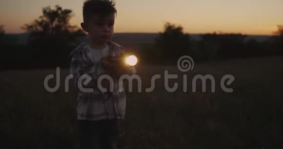 很棒的男孩在日落时玩手电筒视频的预览图