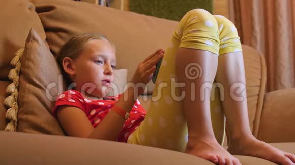 女孩子在沙发上在房间里用手机上网视频的预览图