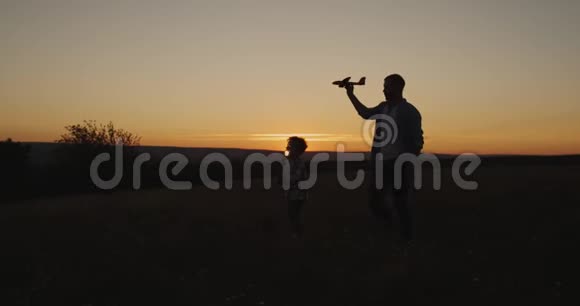 爸爸在日落时和儿子一起玩拿着飞机在一起玩得很开心视频的预览图