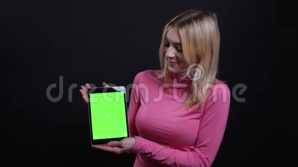 使用平板电脑拍摄年轻漂亮金发女性的特写镜头并显示绿色屏幕与背景隔离相机视频的预览图