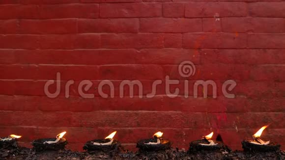 对着红砖墙烧灯寺庙红墙背景上一排燃烧的纪念灯视频的预览图