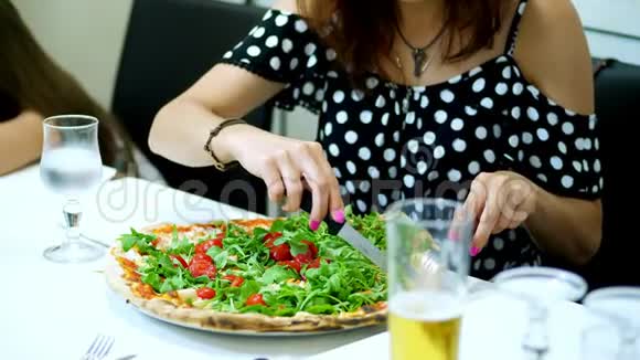 在披萨里一个女人切了一个大的多汁的热的披萨里面有绿色的和樱桃番茄一块一块的披萨视频的预览图