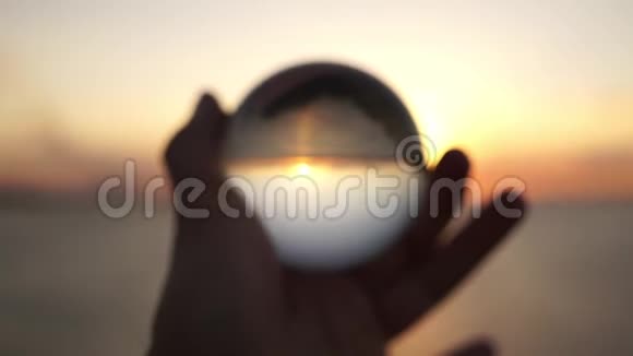 在海上日落的背景下雄手握着一个玻璃球戏剧性的电影镜头剪影视频的预览图