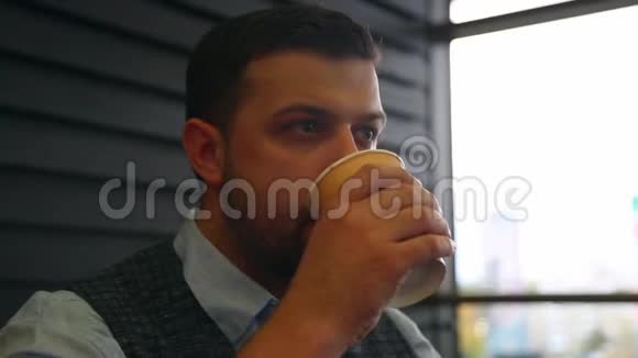 年轻人从一次性纸杯里喝咖啡看着远处特写视频的预览图