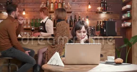 餐馆里的一个年轻女子在笔记本电脑上读课文视频的预览图