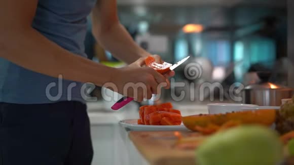 一名年轻人在厨房用新鲜的热带水果为家人准备早餐时慢镜头视频的预览图