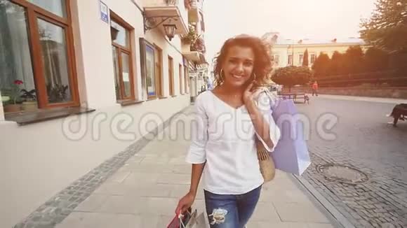 销售消费主义自信的女士带着购物袋在一个城市购物后散步慢动作视频的预览图