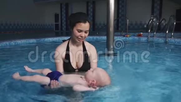 美丽的妈妈教他们在你孩子的背上游泳视频的预览图