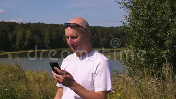 夏天森林里带着手机和短信的快乐男人视频的预览图