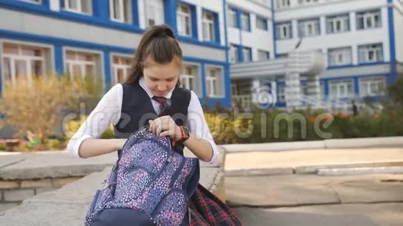 十几岁的女孩坐在学院的院子里在他的背包里找东西视频的预览图