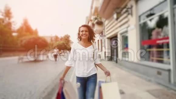 美丽微笑的女人走在街上慢动作一个漂亮的女人拿着购物袋穿过城市视频的预览图