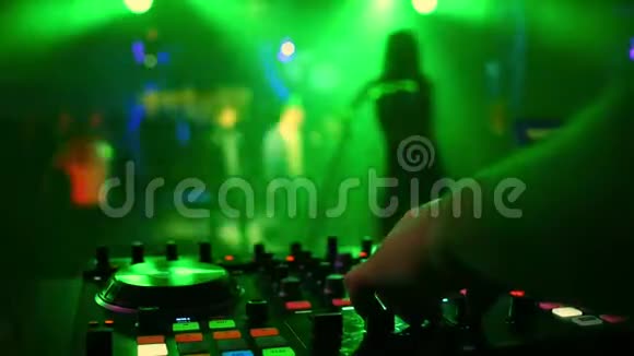 混合控制器与DJ手在夜总会与模糊的剪影跳舞女歌手视频的预览图