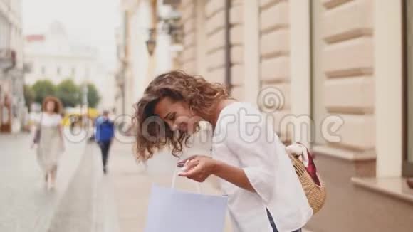时尚购物女性打开一个包裹与购买同时走在城市的街道上购物购物时间视频的预览图