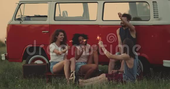 90年代的朋友们在一起玩得很开心坐在一辆复古面包车旁边的草地上玩着视频的预览图