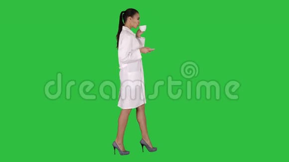 年轻护士在绿色屏幕上散步时放松喝咖啡或茶Chroma键视频的预览图