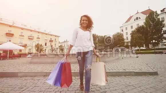 城市概念中的现代女性购物者现代富婆微笑着拿着购物袋走在城市里视频的预览图