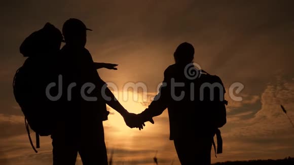 幸福的家庭游客在日落时手持剪影行走徒步旅行者团队合作旅行理念男女夫妇视频的预览图