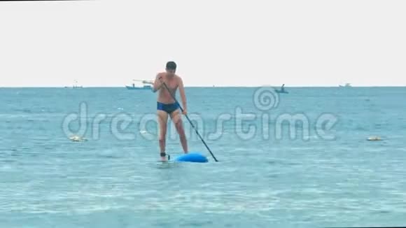 强壮的家伙接近沙滩划桨视频的预览图