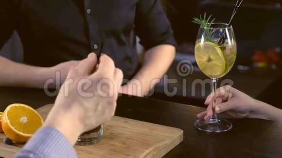 酒吧服务员为柜台上的顾客准备酒精鸡尾酒双手特写视频的预览图