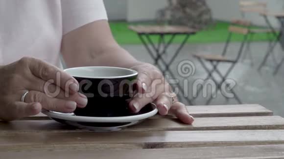 一个特写的女人她的手从桌子上拿了一杯茶大雨视频的预览图