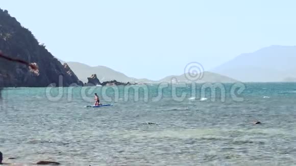 男子站在膝盖移动桨板到海滩视频的预览图