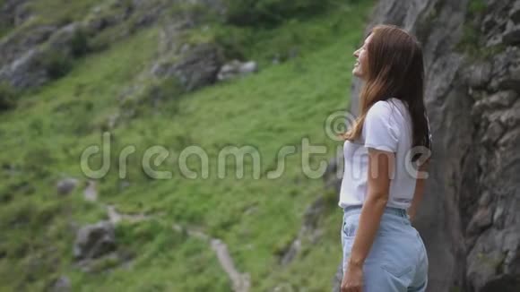 站在山顶上的漂亮女孩举起双手欣赏风景慢动作视频的预览图