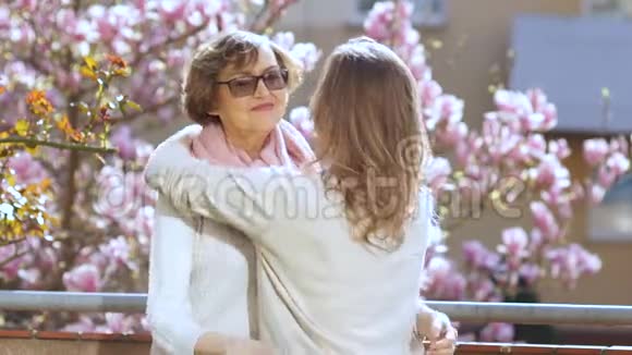 成熟的母亲拥抱她的成年女儿两个女人互相祝贺节日春天的早晨对一个视频的预览图