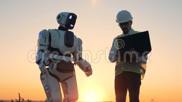 一个工程师和一个机器人在日落背景下关闭视频的预览图
