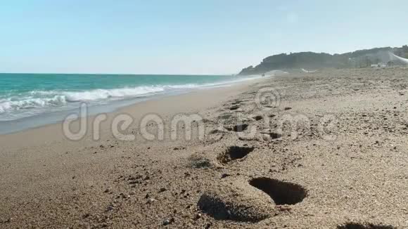 冲破海浪无法辨认的人在海上行走前景上的湿沙迹视频的预览图