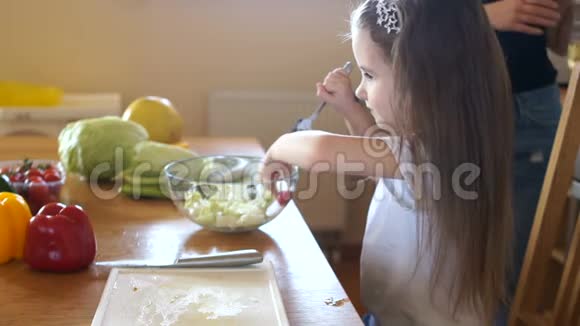 适当的营养一个孩子在厨房里试着用生菜做樱桃番茄妈妈帮手视频的预览图