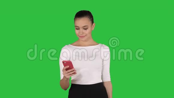 快乐的年轻女人带着智能手机在绿色屏幕上拍摄她的购物袋Chroma键视频的预览图
