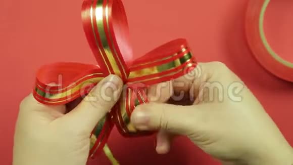 女人双手伸直了粉红色丝带礼物蝴蝶结的花瓣红色背景视频的预览图