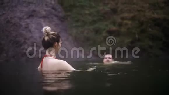 年轻快乐的女人一起在温泉里游泳在冰岛山区山谷旅行的男女视频的预览图