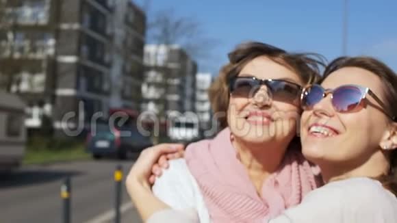 两个女人在微笑画像在一条城市街道上夏日灿烂的阳光戴眼镜的老年和年轻妇女视频的预览图