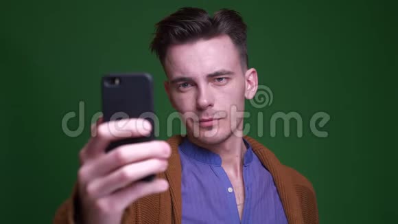 成人魅力男人在手机上自拍的特写镜头背景与绿色隔离视频的预览图