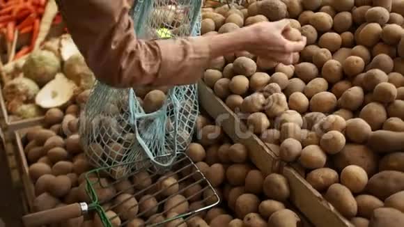 女人把手放在一个串袋里从市场上的木箱里拿出新土豆环保包装零废物视频的预览图