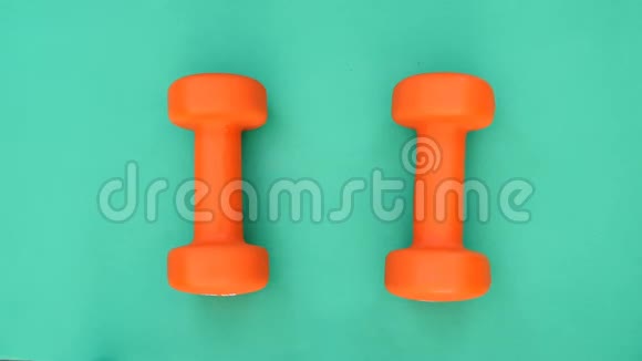做运动两个橙色的哑铃躺在绿色的表面上手拿杠铃视频的预览图