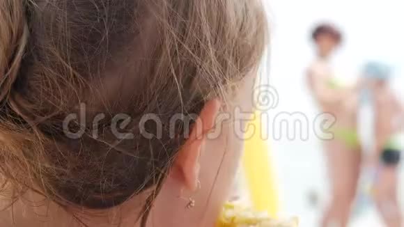 一个金发小女孩在海滩上吃玉米视频的预览图