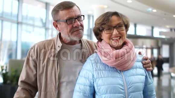 机场休息区的养老金领取者男人搂着女人的肩膀老夫妇等着旅行视频的预览图