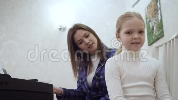 年轻的女老师和小可爱的女孩检查耳朵的音乐视频的预览图