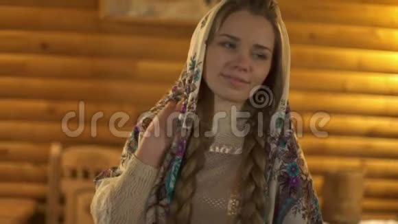 一个戴着围巾的俄罗斯女人在一个温暖柔和灯光的木屋里视频的预览图