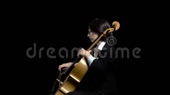 在黑暗的工作室里女人的手在大提琴上打弓黑色背景侧视图视频的预览图